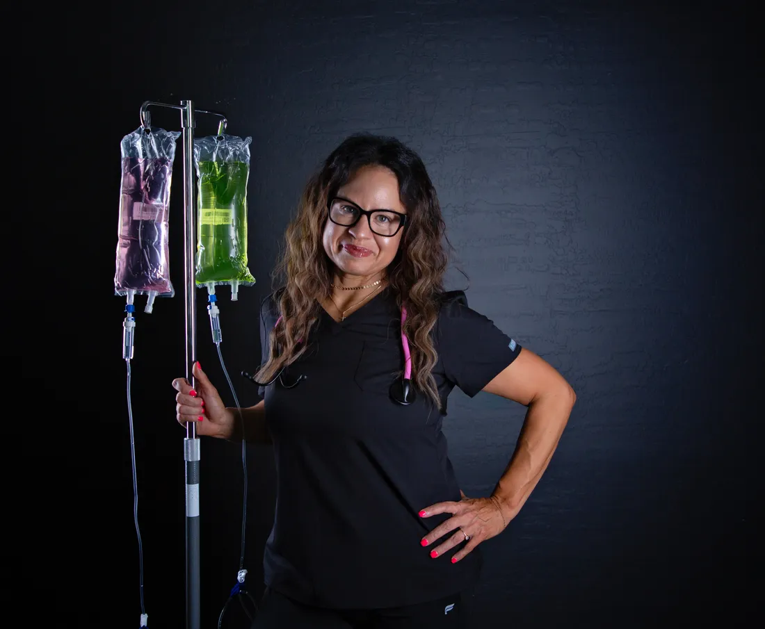 Angela, FNP-C, in scrubs beside an IV drip stand